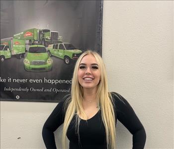 female, black top posing in front of servpro poster